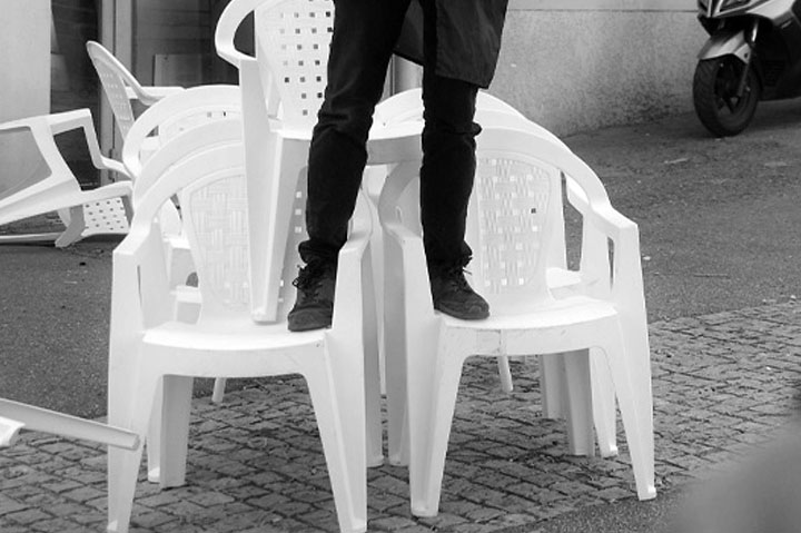 détail de photo d'un comédien debout sur des chaises du spectacle S'asseoir de la Cie Pare-Choc